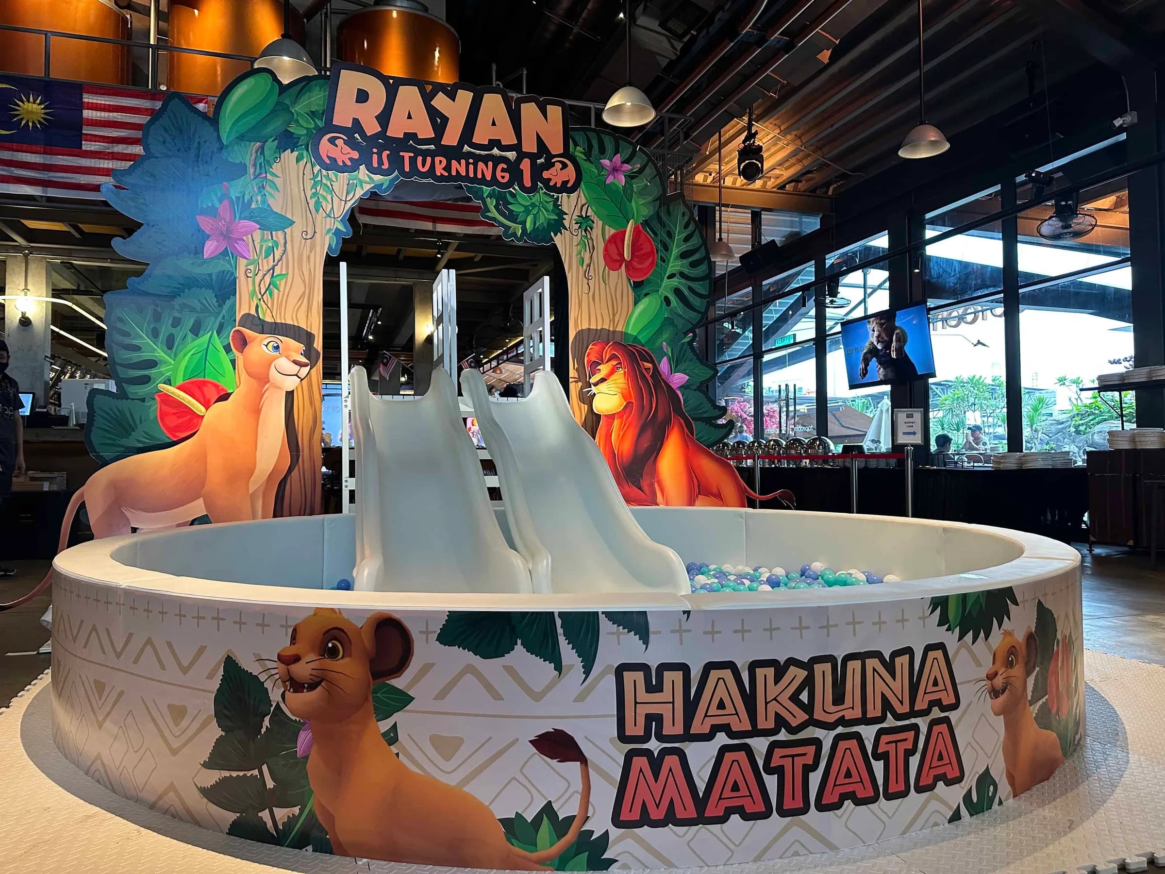 A colorful birthday celebration setup featuring a children's slide and Lion King decorations